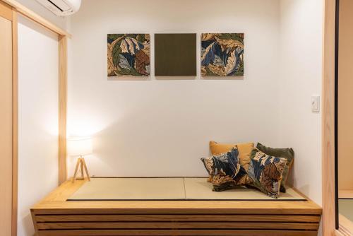 a bed in a room with three paintings on the wall at vacation rental SARAKU 茶楽来 in Osaka