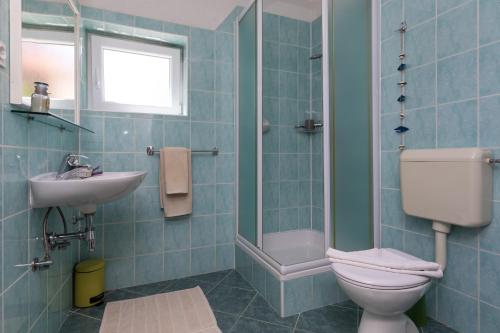 Baño de azulejos azules con aseo y lavamanos en Apartments Paloc - Blue en Bol