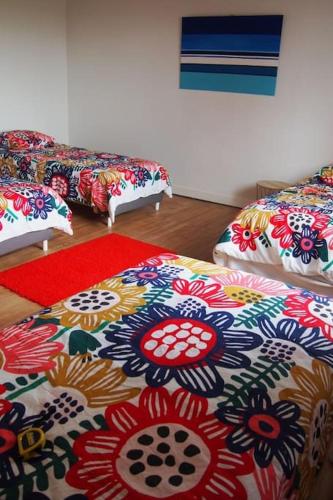 a room with three beds with flowers on them at La Case à Jane, gite familial en pays tarnais in Coufouleux