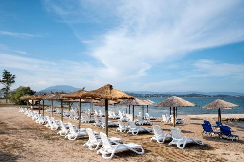 a line of chairs and umbrellas on a beach at Galaxy Hotel in Porto Heli