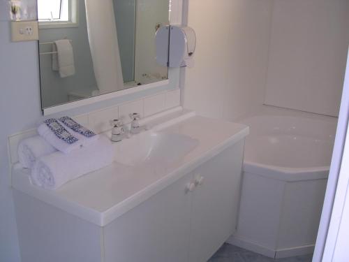 a white bathroom with a sink and a mirror at Acacia Lodge Motel in Mangonui