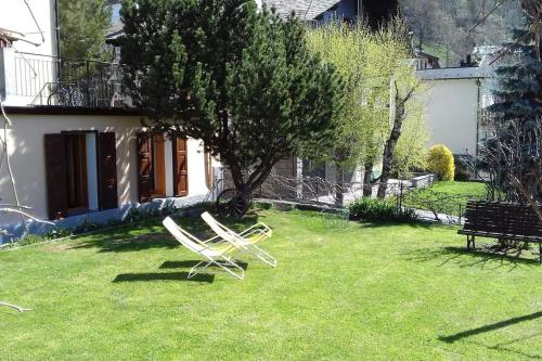 two white chairs sitting in the grass in front of a house at Appartamenti Via Monte Braulio 19 in Bormio