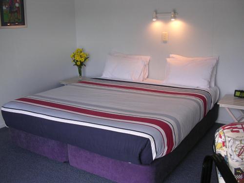 a bedroom with a large bed with white pillows at Acacia Lodge Motel in Mangonui