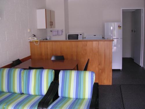 a living room with two chairs and a table and a kitchen at Acacia Lodge Motel in Mangonui