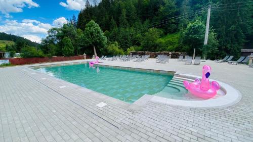 a swimming pool with two pink flamingos in the water at Pension Onelia in Gîrda de Sus