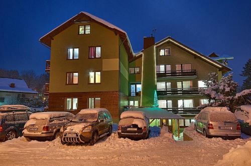 un edificio coperto di neve con auto parcheggiate di fronte di Willa Lena a Szklarska Poręba