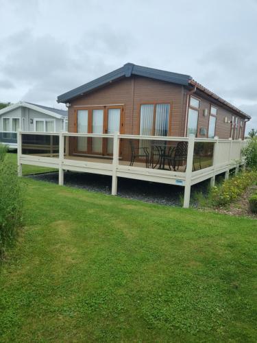 una casa con porche y terraza con bancos en Pemberton Arrondale Lodge, Lakeside View (Haven Lakeland), en Flookburgh