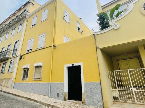 a yellow building with a black door on a street at Casa das Férias in Lisbon