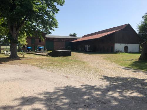 a barn with a tree next to a dirt road at Ferienvermietung Reinstorf in Reinstorf