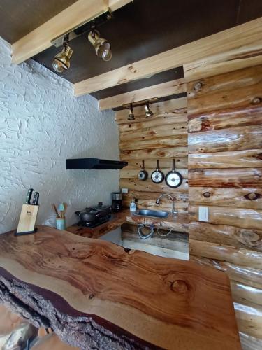 cocina con paredes de madera y mesa de madera en Cabaña en la calera el Pinar en La Calera