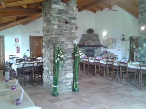 ein Esszimmer mit Tischen und einem Steinkamin in der Unterkunft AGRITURISMO IL RUNCH DI MAJRANO LUCA in Viù