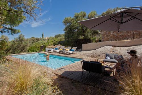 - une piscine avec un parasol et des chaises à côté de la piscine dans l'établissement Villa bodri, maison en pierre avec vue mer et piscine chauffée, à LʼÎle-Rousse