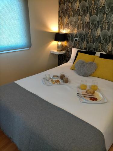 a bed with two plates of food on it at Naturalayos I y Naturalayos II - casas para parejas - jacuzzi in Pelayos de la Presa