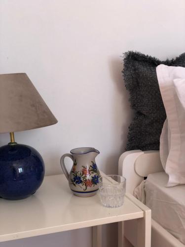 a table with a lamp and a blue vase on it at Villa Antigoni Serifos in Serifos Chora