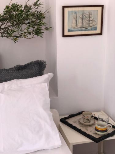 a bed with a white pillow and a tray with a tea set at Villa Antigoni Serifos in Serifos Chora