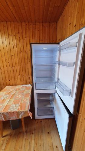 an empty refrigerator with its door open next to a table at Wellapartman Zamárdi in Zamárdi