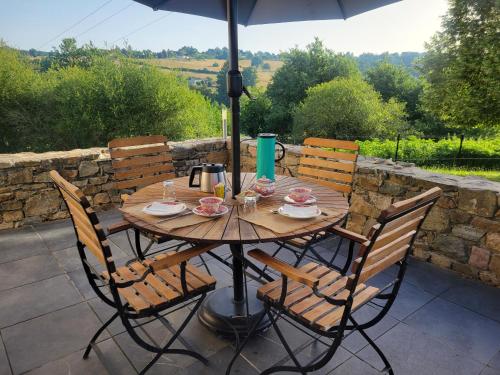 a wooden table with chairs and an umbrella on a patio at Les hauts Brianço in Solignac