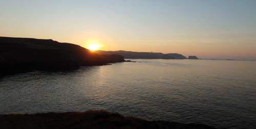 a sunset over a body of water with the sun setting at Tu Casina del Norte in Luanco