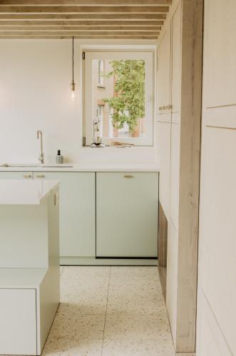 een witte keuken met een wastafel en een raam bij Huisje Nummer Tien in Sint-Laureins