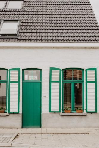 uma casa branca com portas e janelas verdes em Huisje Nummer Tien em Sint-Laureins