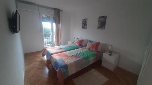 a bedroom with a bed with a colorful comforter and a window at Flora relax house, free parking in Peroj