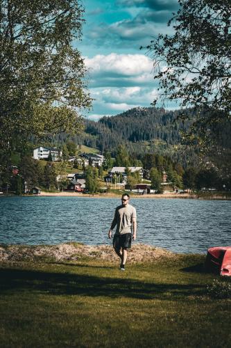 a man walking on the shore of a lake at Morgedal Camping in Morgedal