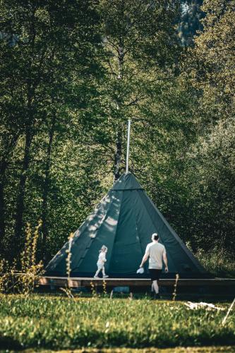 a man and a child walking past a tent at Morgedal Camping in Morgedal