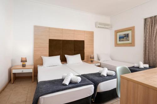 a hotel room with two beds and a desk at Galaxy Hotel in Porto Heli