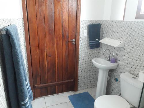 a bathroom with a wooden door and a toilet and a sink at A Taberna - chalés in Alto Paraíso de Goiás