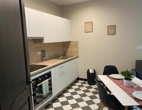 una cocina con armarios blancos y una mesa con suelo de tablero de ajedrez en AILE DU CHATEAU 6 personnes, en Lebétain