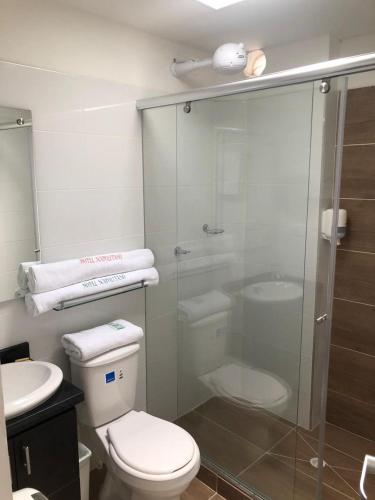 a bathroom with a toilet and a glass shower at Hotel Napolitano in Villavicencio