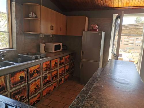 una cocina con nevera y microondas en Skippers Backpackers CC, en Walvis Bay