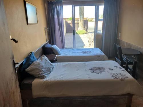 two beds in a hotel room with a balcony at Namibia Skipper Services in Walvis Bay