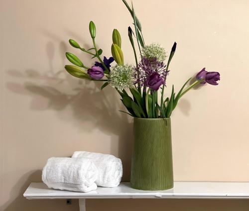 eine grüne Vase mit lila Blumen auf einem Regal in der Unterkunft White Horse Lodge in Waitsfield