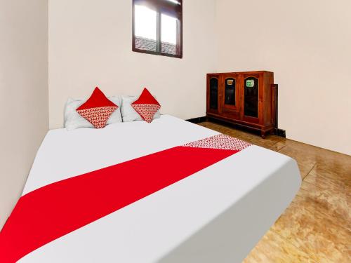 a bedroom with a red and white bed and a cabinet at OYO Homes 91134 Desa Wisata Tebing Lingga 