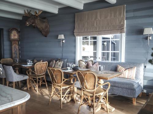 Danebu Kongsgaard - Boutique Hotel في Aurdal: غرفة طعام بجدران زرقاء وطاولات وأريكة