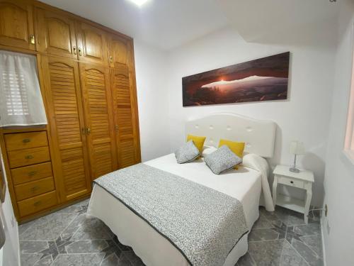 1 dormitorio con cama blanca y almohadas amarillas en Luar del Carmen, en Callao Salvaje