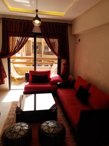 uma sala de estar com mobiliário vermelho e uma grande janela em Agréable appartement au coeur de Guéliz, Marrakech em Marrakech