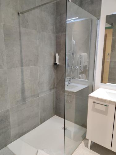 a shower with a glass door in a bathroom at Hôtel de la Tour in La Tour-du-Pin