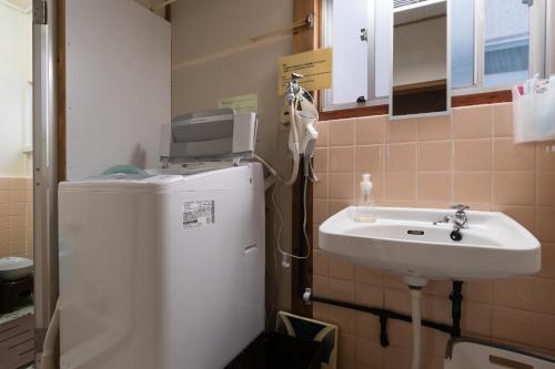 a small bathroom with a sink and a refrigerator at Unique joy House in Okayama