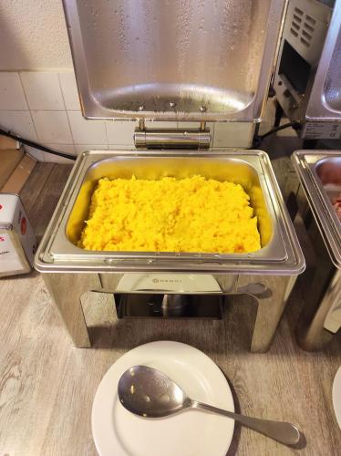 a dish of food in a pan with a plate and a spoon at Hotel Bacco Rooms and Breakfast in Pietra Ligure