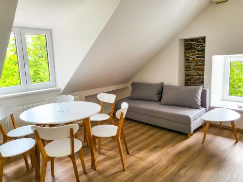 uma sala de estar com uma mesa e cadeiras e um sofá em Apartmány u Koláčků em Hartmanice