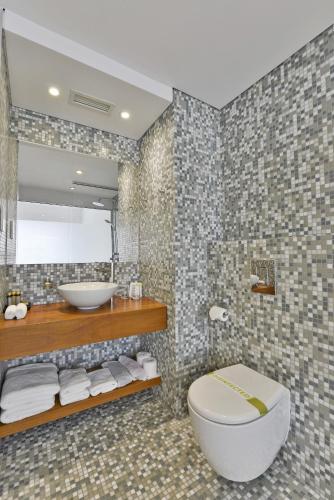a bathroom with a toilet and a sink and a mirror at Napa Mermaid Hotel & Suites in Ayia Napa