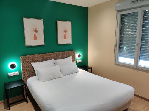 a bedroom with a large bed with a green wall at Hôtel de la Tour in La Tour-du-Pin