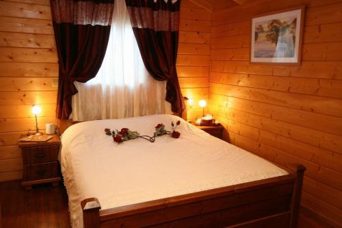 a bedroom with a bed with two roses on it at Spa Chalets In Olive Grove in Eli Ad