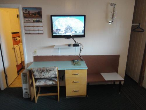 a room with a desk and a tv on a wall at Airport Inn Motel in Quesnel