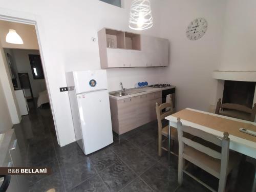 a kitchen with a white refrigerator and a table at B&B BELLAMI' in Tuglie