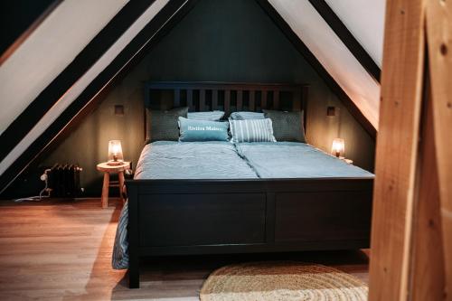 a bed with blue sheets and pillows in a attic at Het Houten Huisje 84 Luxe vakantiewoning Zuid Limburg in Simpelveld