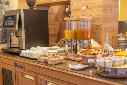 a buffet line with food and drinks on a counter at Hotel Lo Scoiattolo in Courmayeur