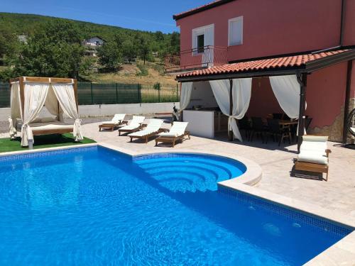 a swimming pool with chairs and a house at Villa Emili in Posušje